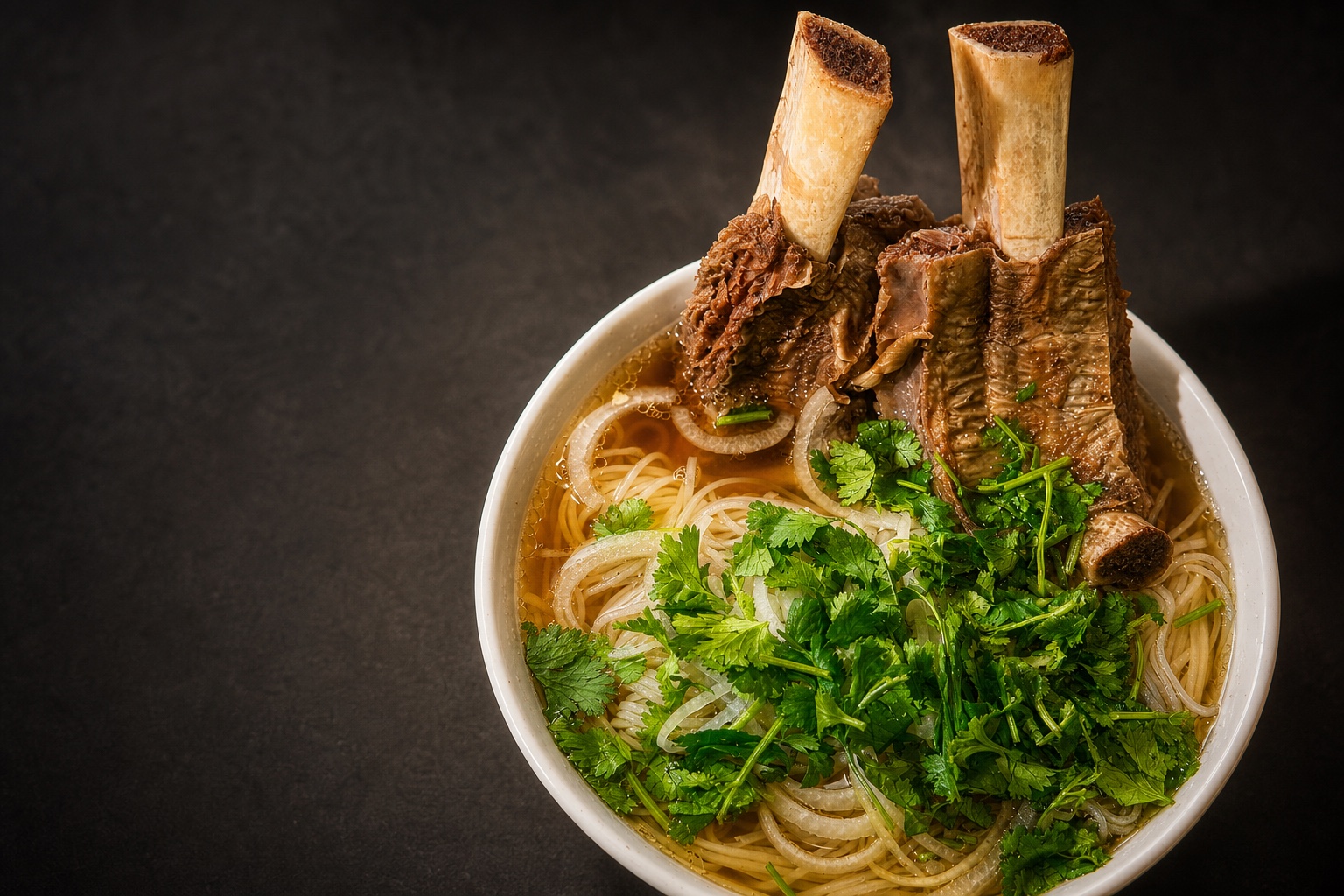 A large bowl of phở sườn bò with beef rib, pork roll, herbs, and clear broth