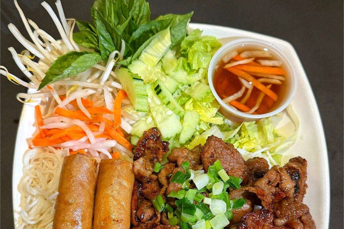 Vermicelli plate with grilled pork, egg rolls, herbs, and nước chấm