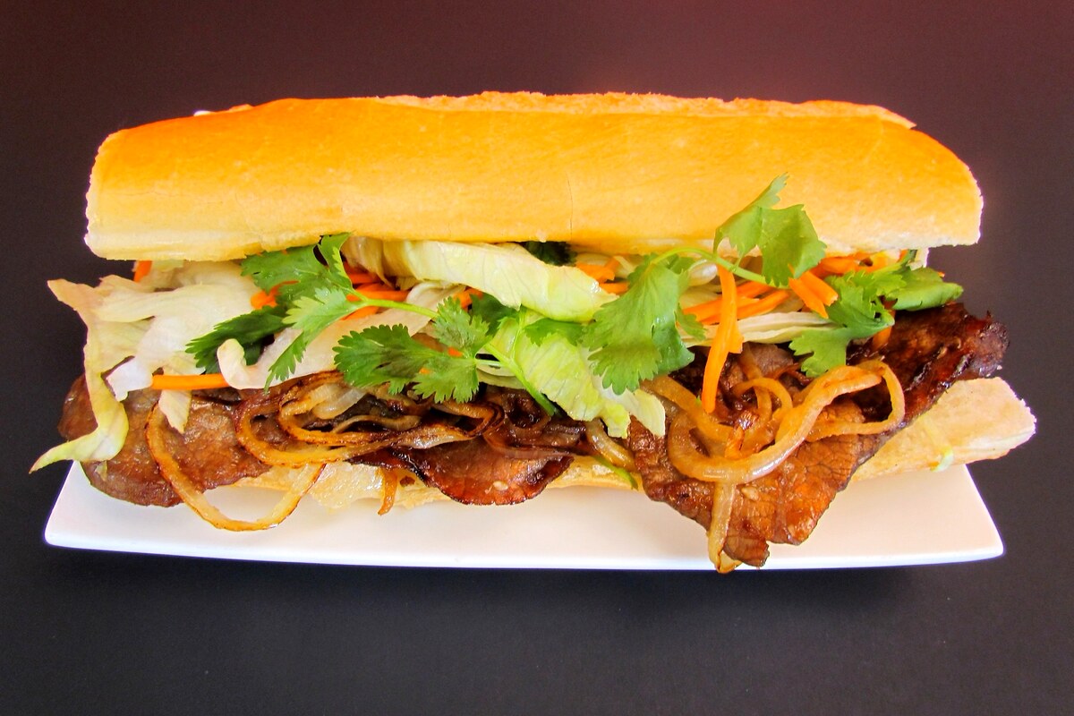 Bánh mì sandwich with grilled meat, pickled vegetables, herbs, and cucumber